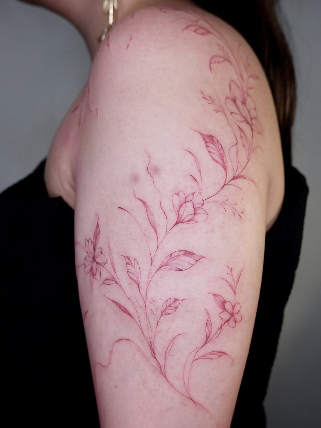 Freehanded red-ink floral half-sleeve tattoo